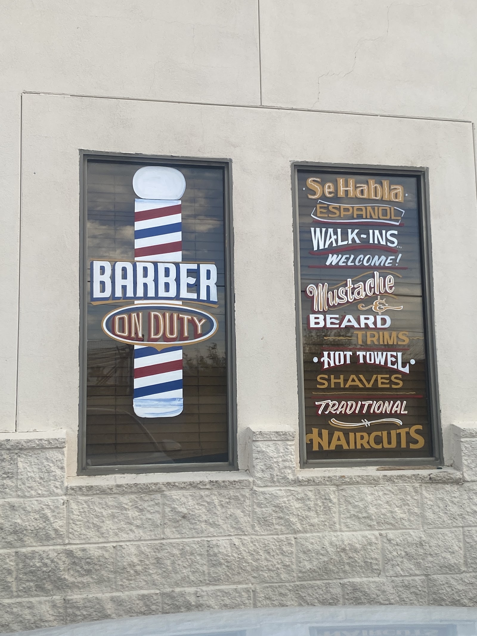 Painted barbershop windows reading Barber On Duty alongside a services list