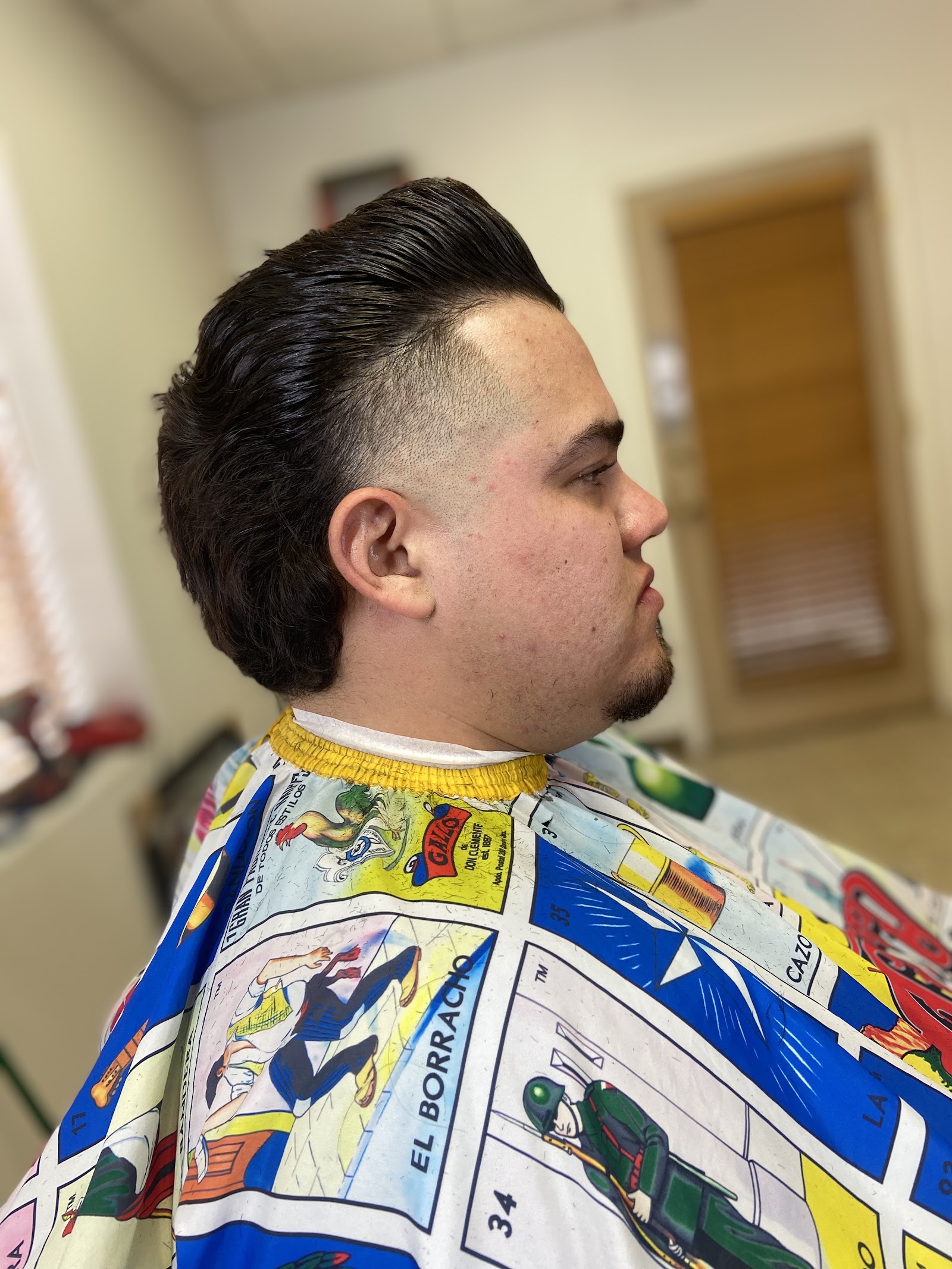 Side profile of a man's fresh pompadour haircut with faded sides